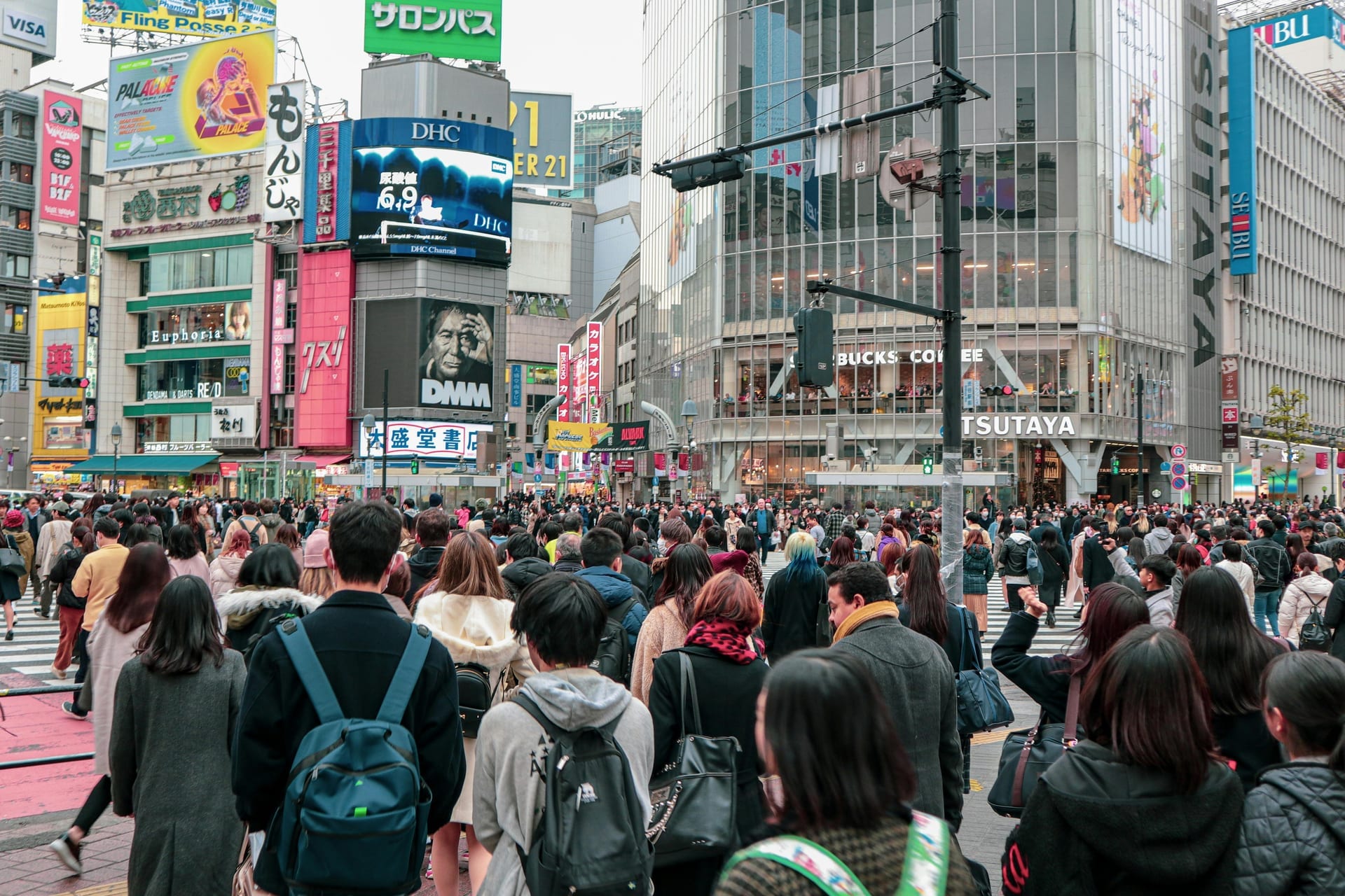 Crowds of people crossing Shibuya Crossing from street level with the Starbucks Tsutaya building visible in the background